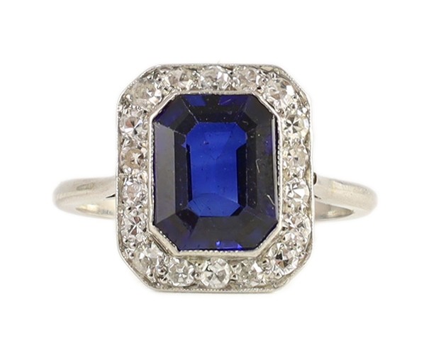 A 1920's platinum, emerald cut synthetic sapphire and millegrain set diamond rectangular cluster ring, with canted corners
